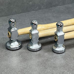 May include: Three silver metal hammers with wooden handles. The hammers have a round head and a flat striking surface. The handles are light brown and have a smooth finish.