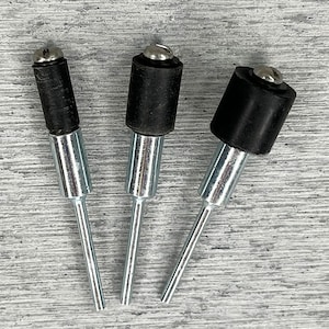 May include: Three silver sanding drums with black rubber sanding pads. The drums are different sizes.