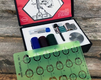 May include: A green plastic ring sizing template with 18 numbered ring sizes. The template is part of a kit for a ring trimmer, which is also pictured in the image. The kit includes a tool for trimming rings, a set of mandrels, and a small screwdriver.