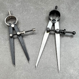 May include: Two metal calipers, one black and one silver, with adjustable arms and a screw adjustment knob. The calipers are used for measuring the diameter of objects.