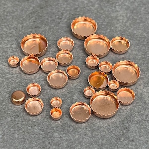 May include: Assortment of copper-colored metal cup-shaped embellishments with scalloped edges. The embellishments are of various sizes.