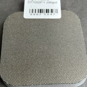 May include: A gray, rectangular sanding block with a textured surface. The block has a white label with the text "mfg # 110074 ST7682P = 280gnt" and a barcode with the number "0007 5947".