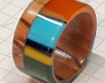May include: A wooden ring with a multi-colored resin inlay. The inlay features stripes of orange, turquoise, blue, yellow, and green.