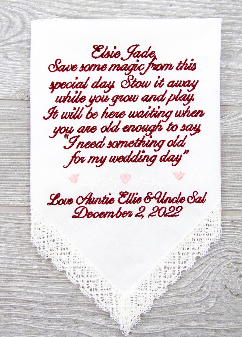 Puede incluir: Un pa&ntilde;uelo blanco con ribete de encaje y texto bordado en rojo y rosa. El texto dice "Elsie Jade, Save some magic from this special day Stow it away while you grow and play. It will be here waiting when you are old enough to say "I need something old for my wedding day." Love Auntie Ellie & Uncle Sal December 2, 2022"