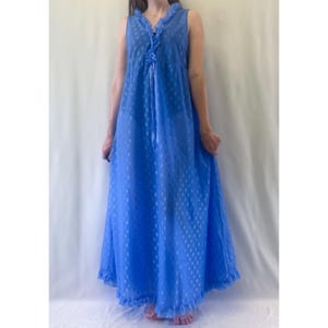 May include: A floor-length blue sleeveless nightgown featuring a repeating white geometric pattern. The garment has a V-neckline with ruffled trim, a ribbon tie detail at the centre chest, and a ruffled hemline at the bottom of the skirt.