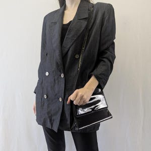 May include: A black double-breasted blazer with a black patent leather shoulder bag.