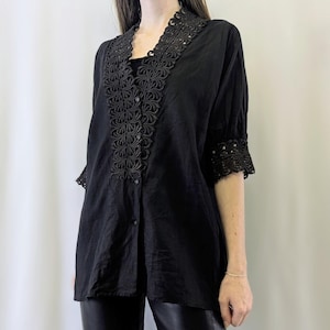 May include: A black button-up shirt with a lace trim around the neckline and sleeves. The lace is a delicate floral pattern.