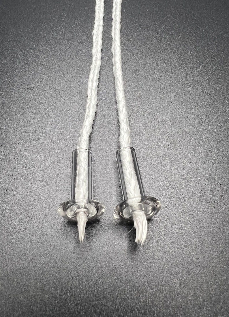 May include: Two white braided wicks with clear glass bases and metal rings. The wicks are designed for use in oil lamps.