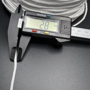May include: Close-up of a white cotton cord being measured with a digital caliper. The caliper reads 2.8 mm.