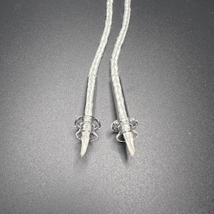 May include: Two clear glass dab tools with white braided cords attached. The tools have a pointed tip and a small ring at the top.