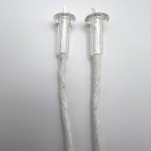 May include: Two white cotton wicks with clear plastic tops. The wicks are braided and have a small loop at the top.