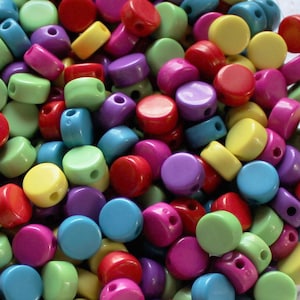 May include: A large pile of colorful round plastic beads. The beads are in various shades of red, yellow, green, blue, and purple.