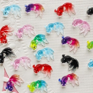 May include: Assortment of colorful glass goldfish charms with iridescent finishes. The charms are in various colors, including red, blue, green, black, and pink.