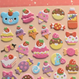 May include: A sheet of colorful, 3D foam stickers featuring various cute food and dessert designs, including donuts, cupcakes, ice cream cones, candy, and fruit. The sheet is labeled "Stickers" and "Made in China".
