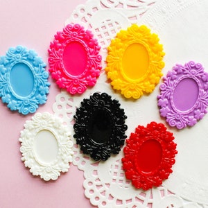 May include: Assortment of seven decorative oval-shaped plastic frames with ornate floral designs. The frames are in various colors, including blue, pink, yellow, red, black, and purple.