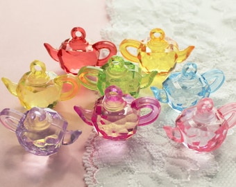 May include: A collection of eight colorful, miniature teapot charms made of clear plastic. The teapots are in various shades of pink, purple, blue, green, yellow, and red.