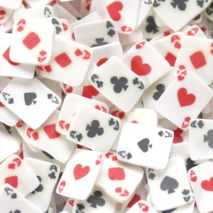 May include: A close-up of a pile of white playing cards with red and black suits. The cards are all aces and have a variety of suits, including hearts, diamonds, clubs, and spades.