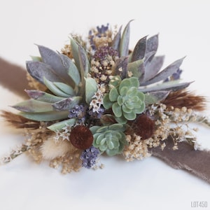 May include: A green succulent floral arrangement with dried flowers and brown accents. The arrangement is tied with a brown ribbon.