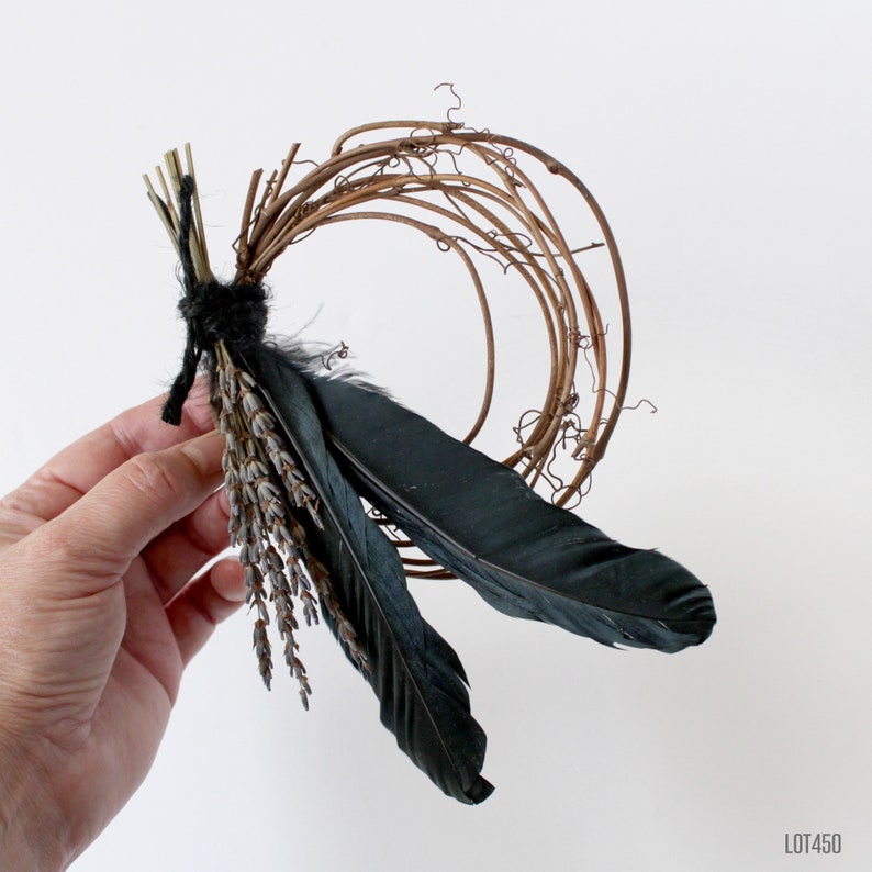 Puede incluir: Una corona hecha de ramitas marrones con plumas negras y ramitas de lavanda secas adjuntas.