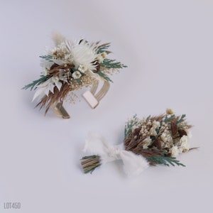 May include: Two dried flower arrangements, one a wrist corsage with a gold metal band and the other a small bouquet with a white ribbon.