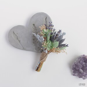 May include: A small bouquet of succulents and lavender flowers tied with twine, arranged on a gray heart-shaped background.