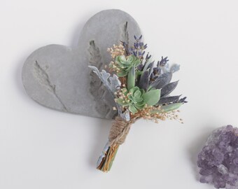 May include: A small bouquet of succulents and lavender flowers tied with twine, arranged on a gray heart-shaped background.