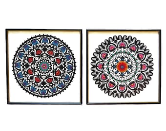 May include: Two framed black and white mandala designs with colorful floral patterns. The mandalas are framed in black frames with white mats.