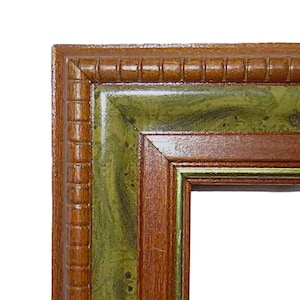 May include: Close-up of a decorative picture frame corner. The frame features a dark brown, textured outer edge, a green marbled inner section, and a thin gold inner trim. The frame is designed to hold a picture.