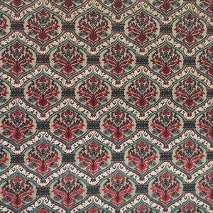 May include: A red, green, and white patterned fabric with a repeating floral design.