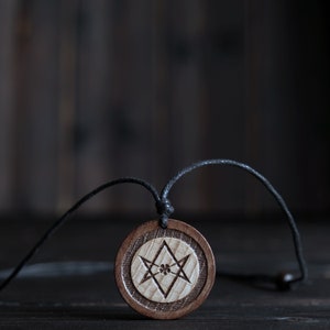 May include: A wooden pendant with a black cord, featuring a carved Star of David design.