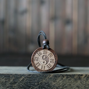 May include: A wooden necklace with a round pendant featuring a yin yang symbol and the words "HOW & THE BEST WAY TO DO MY CLASS BUT ON THE JOURNEY"