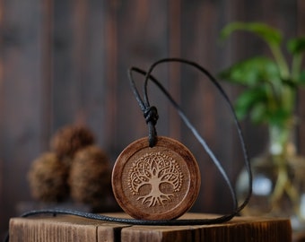 May include: A wooden pendant necklace with a tree of life design. The pendant is brown and has a black cord.
