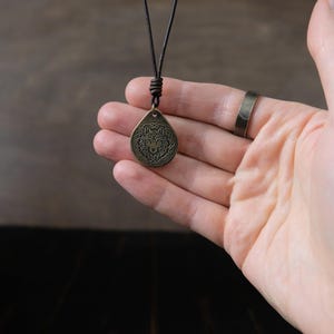 May include: A brown leather cord necklace with a bronze pendant featuring a wolf's head design.