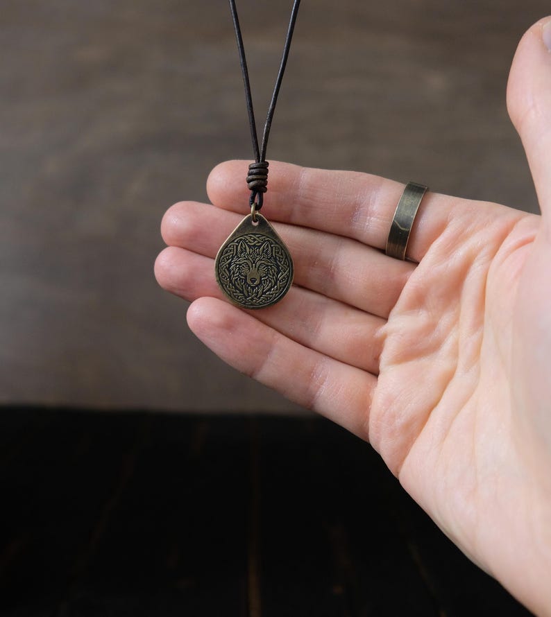May include: A brown leather cord necklace with a bronze pendant featuring a wolf's head design.