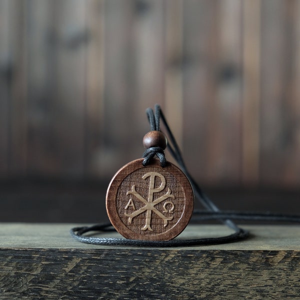 Collana/pendente Chi Rho. Realizzato in legno di sicomoro massiccio. Forma rotonda. Colore marrone. Cordoncino in cotone regolabile. Personalizzazione del testo.