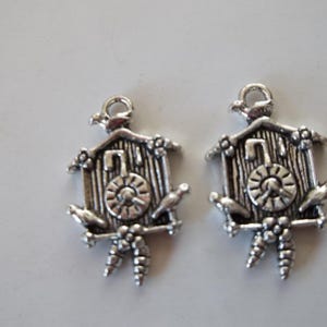 May include: Two silver charm pendants shaped like cuckoo clocks with birds and a clock face.