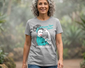 May include: A heather gray short-sleeve t-shirt featuring a graphic of a person with a teal headscarf and teal shirt flexing an arm. The text reads Ovarian Cancer Warrior and UNBREAKABLE in white and teal lettering on the front of the garment.