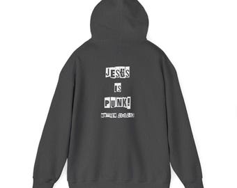 May include: Dark gray hoodie with a hood. The back of the hoodie features the text "JESUS IS PUNK!" in a cut-out style, with "MATTHEW 21:12-13" below. The hoodie is a casual garment.