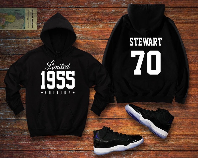 May include: Black hooded sweatshirt with white text "Limited 1955 Edition" on the front and "STEWART 70" on the back. A pair of black and white sneakers are also pictured.