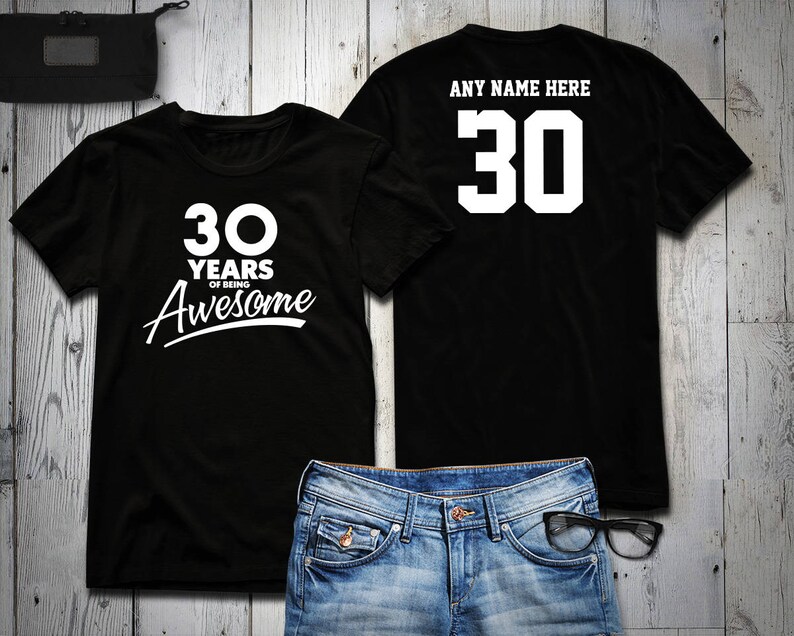 May include: Two black t-shirts with white text. One shirt says "30 Years of Being Awesome" and the other says "Any Name Here 30".