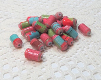 May include: A pile of colorful paper beads in shades of pink, green, and blue. The beads are cylindrical and have a slightly textured surface.