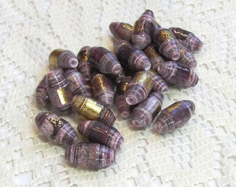 May include: A collection of purple and gold paper beads. The beads are rolled and have a textured, layered look.