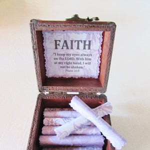 May include: A wooden box with a hinged lid, decorated with a floral design and the word "FAITH" in large letters. The box is open, revealing a stack of rolled up papers with a purple and white floral pattern. The inside of the box has a quote from Psalm 16:8, "I keep my eyes always on the LORD. With him at my right hand, I will not be shaken."