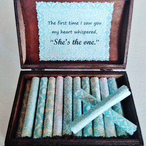 May include: A wooden box with a blue and white patterned lid. The lid has a message that reads "The first time I saw you my heart whispered, 'She's the one.'" The box is filled with rolled up pieces of paper with a similar blue and white pattern.
