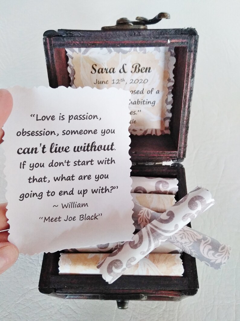 May include: A wooden box with a quote about love and a small tag with the names Sara & Ben and the date June 12th, 2020. The box is open and contains several rolled up pieces of paper.