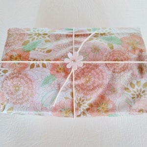 May include: A gift box wrapped in floral patterned paper with a pink flower embellishment tied with twine.