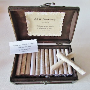 May include: A wooden box with a hinged lid, open to reveal a collection of rolled up papers. The box is decorated with a quote from Hermann Hesse: "If I know what love is, it is because of you." The box also includes a quote from Ben Folds: "I love you more than I have ever found a way to say to you."