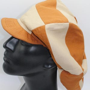 May include: A brown and white striped fabric hat with a short brim. The hat is made of a soft, comfortable material and has a relaxed, casual style.