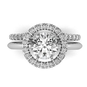 May include: A silver engagement ring set with a round center stone and a halo of smaller stones. The band is also set with smaller stones.