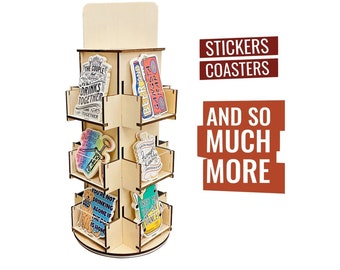 May include: A wooden display stand with multiple shelves, showcasing a variety of stickers and coasters. The stand is designed to rotate, allowing for easy viewing of the products. The text "Stickers Coasters And So Much More" is displayed on the right side of the image.